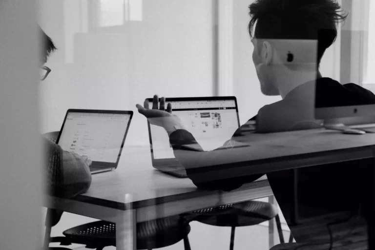 Photo noir et blanc de deux personnes travaillant sur des ordinateurs portables
